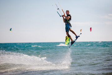 Professional kiter does the difficult trick. A male kiter rides against a beautiful background of waves and performs all sorts of maneuvers.