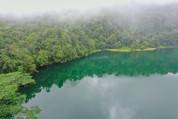 Idyllic shot of the green Rana Mese lake on Flores, surrounded by rainforest with hazy clouds.