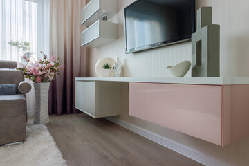 The modern style of the living room in pink and white colors with a cabinet and TV