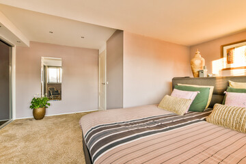 a bedroom with a bed, dresser and mirror in the corner wall to the right is an open door that leads...