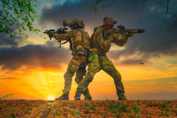 The soldiers turned their backs on each other then aiming to fire around on the sundown background.