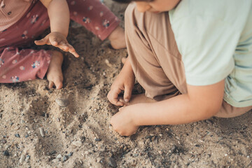 Top view of the hands of some children digging in the stony sand from the back of the house from the village. Summer vacation. Creative concept. Little garden.