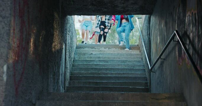 Shot photo of delighted schoolgirls running down stairs laughing having fun relaxing singing after busy day at school.