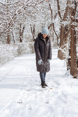 Naklejka premium A woman stands in warm clothes in a winter park.
