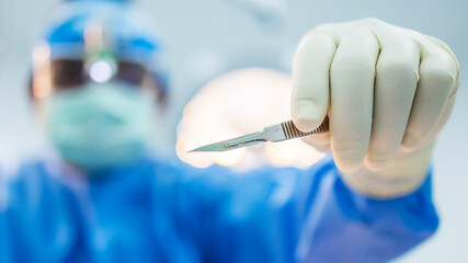 Selective focus at surgeon's hand with blur background.Doctor or surgeon made skin incision in...