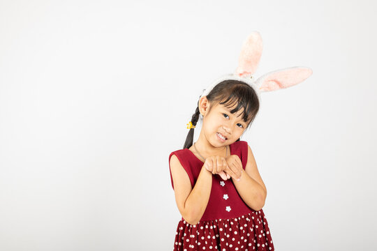 Happy Easter Day. Smile Asian little girl wearing bunny ears make hands act like a rabbit studio shotr isolated on white background with copy space, Easter eeasonal sale and discount