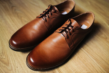 Brown leather shoe. Groom getting ready for the wedding. Wearing clothes background. Dressing up male fashion. Elegant shoes isolated on wooden floor. Wedding fashion clothing background.