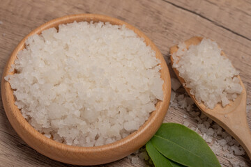 Sea salt in wooden cup on gray background