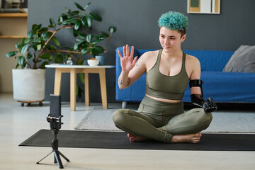 Girl saying hi to her followers during broadcasting live while exercising in the room