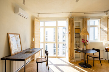 Beautiful and cozy workplace with wooden table, chair and picture frame near the window in apartment. Home office concept. Real photo