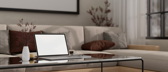 Close-up image of laptop mockup and decor on modern coffee table in cozy living room.