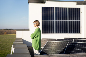 Woman on the roof of her house with a solar station installed on it. Happy owner of...
