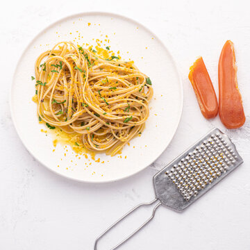 Spaghetti pasta with bottarga (dried tuna or mullet caviar) on a white table. Classic sea dish of Sardinia and Sicily islands. Italian healthy cuisine, square crop