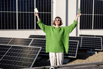 Portrait of happy woman holds euro banknotes saved due to the generation of energy from a solar...