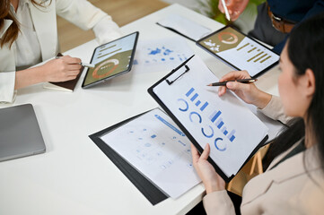 Close-up image of professional millennial Asian businesswoman reviewing financial data on report