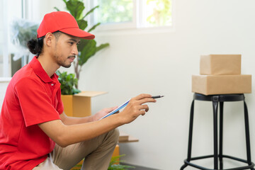 Service, delivery asian man, male checking list stuff, parcel or cardboard box, carton in warehouse before deliver to customer address. Courier working in uniform. Moving in new relocation.