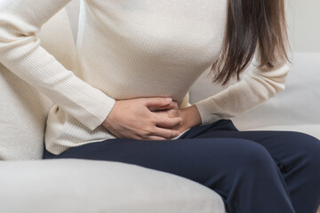 Flatulence asian young woman, girl hand in stomach ache, suffer from food poisoning, abdominal pain and colon problem, gastritis or diarrhoea. Patient belly, abdomen or inflammation, concept.