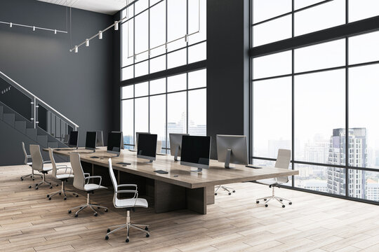 Modern office hall interior design with stylish wheel chairs around big conference wooden table with computers on parquet floor, dark wall background and city view from panoramic window. 3D rendering