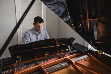 Close up of a man playing baby grand piano
