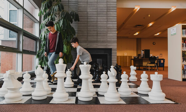 Two young boys playing giant chess game in a library