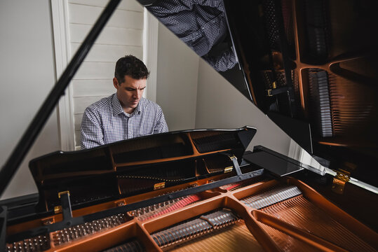 Close up of a man playing baby grand piano