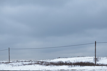 Two wooden telegraph poles and grey sky in winter