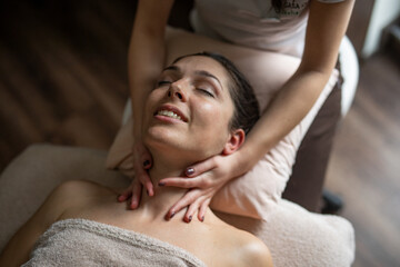 Fototapeta na wymiar A beautiful young woman is enjoying a massage in a SPA centre