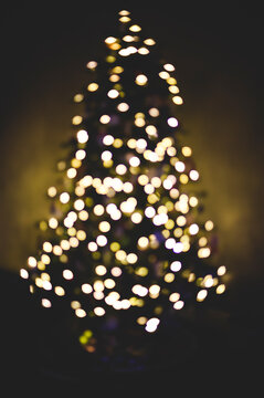 Blurred white Christmas lights on a Christmas tree in the dark.