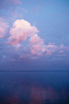 Pink and white clouds and blue sky at sunset with reflection on lake