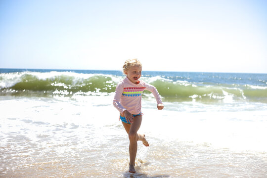 girl running away from waves at waters edge in sag harbor new york
