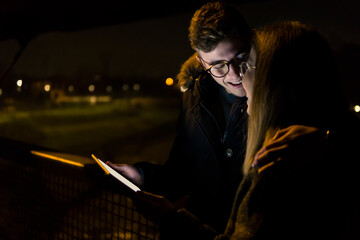 Romantic Couple laughing in the evening with light of a tablet device