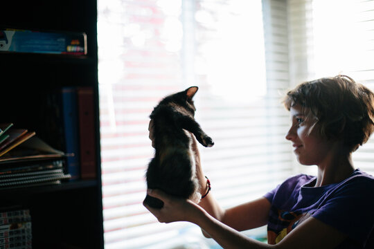 Girl holds kitten up to look at it