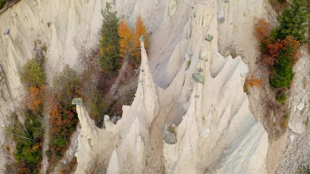 4k drone flight down footage (Ultra High Definition) of Earth pyramids of Platten - Spiky sand towers formed by water erosion and accessed by a woodland trail dotted with sculpture.