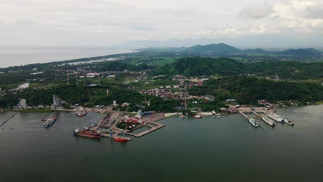 Wide view of cargo container transport ship and ferries parked at the port of Poto Tano Harbour Sumbawa Indonesia, silhouette sunset. Logistic industry, freight transportation. 4K Drone aerial