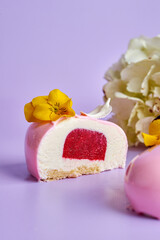 Cut and whole mousse cake on a pink background in a composition with flowers.