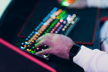 Guy playing gaming game on computer keyboard close up hands at club.