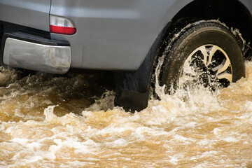 Muddy rain from a heavy rainy season flooded main roads connecting the district, making it difficult for cars to pass through and causing engine failures, in motion, car insurance concept.