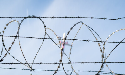 Barbed wire detail. Airplane in the background.