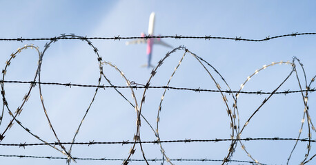 Barbed wire fence detail. Airplane in the background.