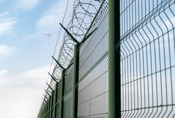 Fototapeta na wymiar Barbed wire fence detail. Blurred airplane in the background.