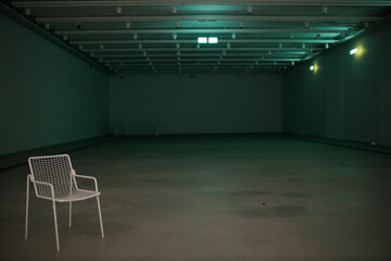 Lonely white chair in large dark room indoor with copy space