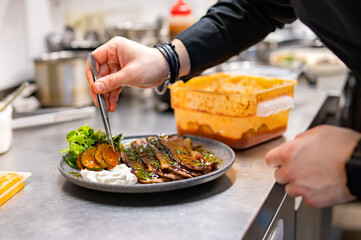 professional chef's hands cooking sliced meat beef brisket with salad in restaurant kitchen