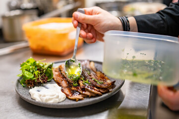 professional chef's hands cooking sliced meat beef brisket with salad in restaurant kitchen