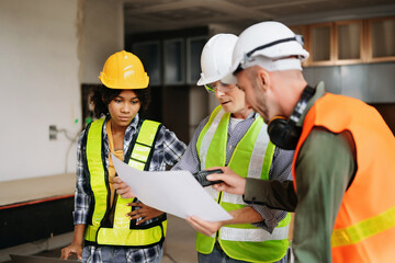 Architect caucasian man and woman working with colleagues mixed race in the construction site. Architecture engineering on big project. Building in construction process interior.