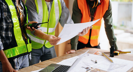 Contractor and architect looking at plan, tablet, laptop and talking about working on big project....
