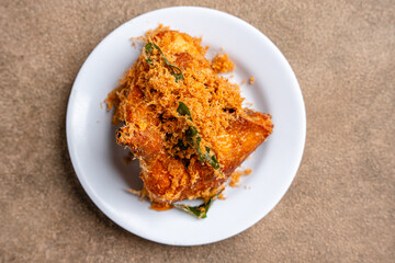 Ayam Goreng Padang. Traditional fried chicken with spice crumbs from Minangkabau, West Sumatra. served on white plate 
