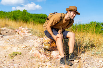 Caucasian man traveler suffering knee pain during hiking on mountain hill. Handsome guy with...