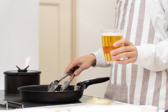 キッチンで料理をしながらビールを飲む40代の男性