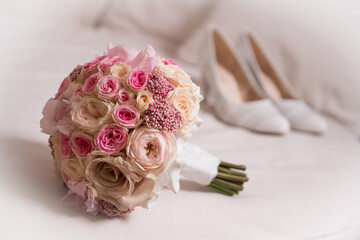 the bride's bouquet and the bride's shoes on the bed. 
white bride's shoes on the bed
