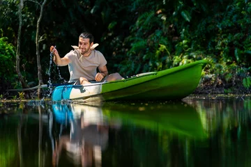Foto op Canvas Caucasian man resting on kayak boat during kayaking at mangrove forest on summer vacation. Handsome guy enjoy outdoor lifestyle canoeing on lake. Environmental ecotourism and solo travel concept. © CandyRetriever 